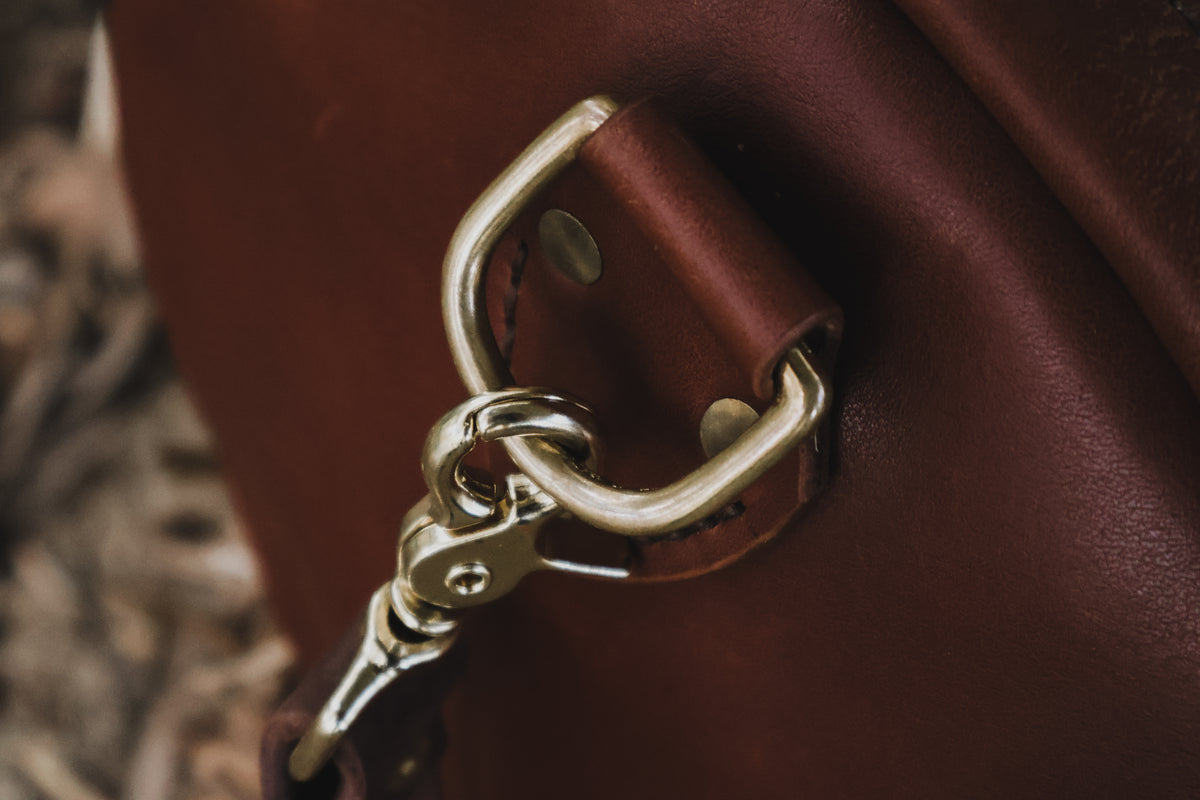 Close-up of The Bully Duffel Bag’s solid-brass D-ring and swivel clasp secured to reinforced full-grain leather.