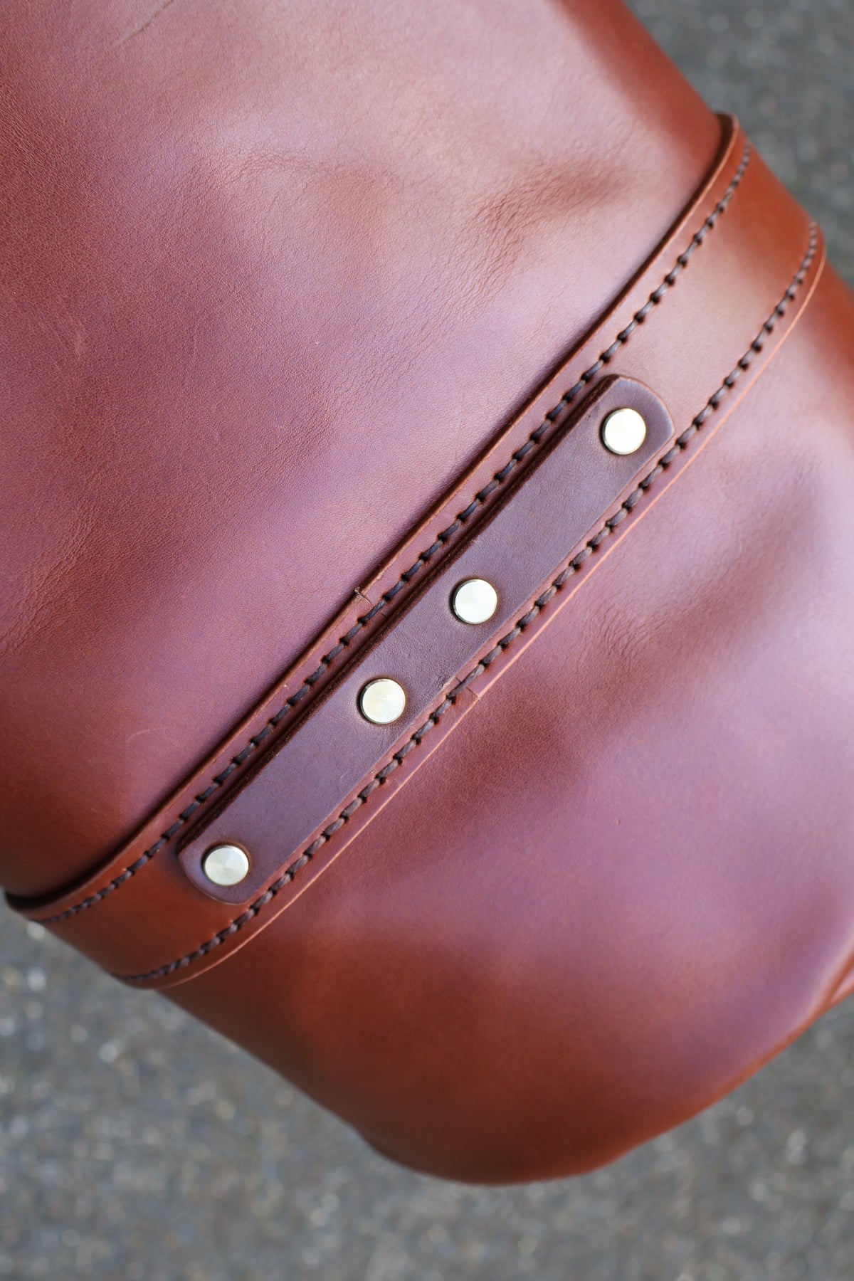 Close-up of The Bully Duffel Bag’s chestnut full-grain leather, reinforced stitching and metal rivets.